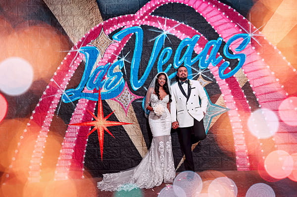 newlyweds standing in front of a Las Vegas Mural at the chapel drive thru