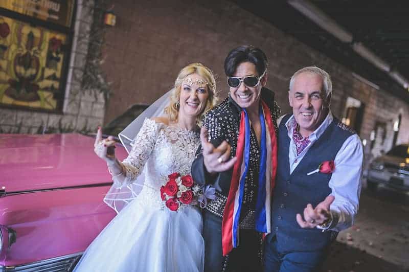 A couple standing next to Elvis on their wedding day in Vegas